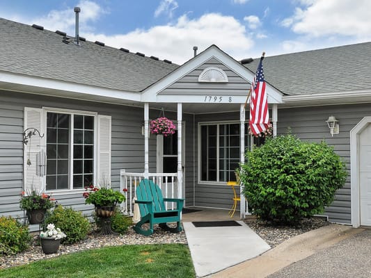 Front entrance of a senior living facility with flowers and a flag