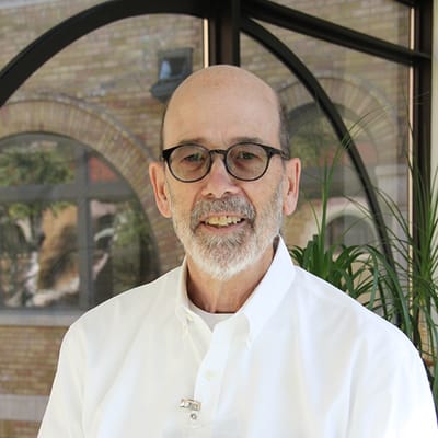 A man with glasses smiling indoors