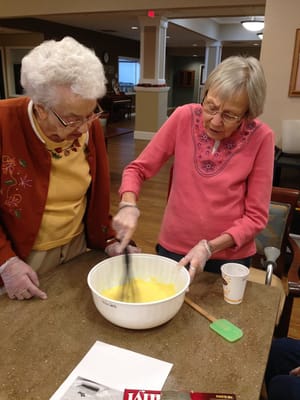 Two residents mixing ingredients in an activity room