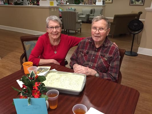 Couple celebrating with cake in a cozy common area