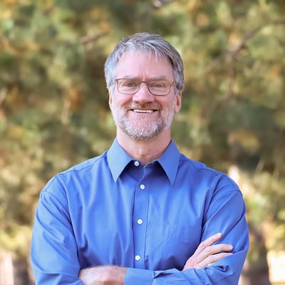 A smiling man in a blue shirt standing outdoors