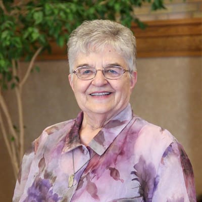 A senior resident smiling wearing a colorful blouse.