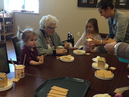 Seniors and children making gingerbread houses together