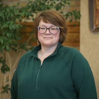 Staff member posing indoors with greenery in the background