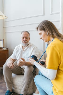 A caregiver taking a resident's blood pressure in a cozy room