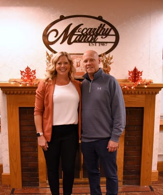 Two staff members posing in a warmly decorated lobby