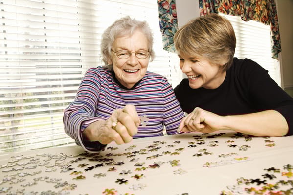 Two women working on a puzzle in a bright room