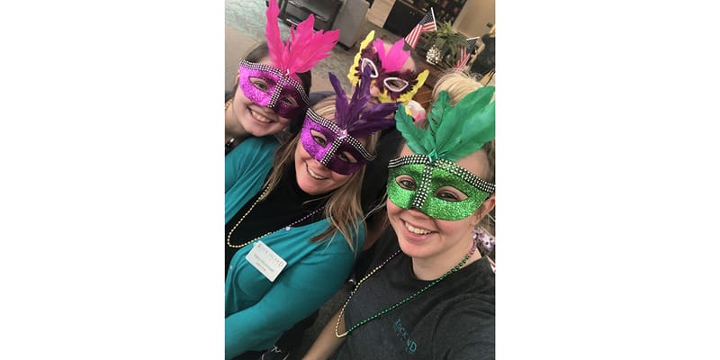 Residents and staff wearing colorful masks at a festive event.