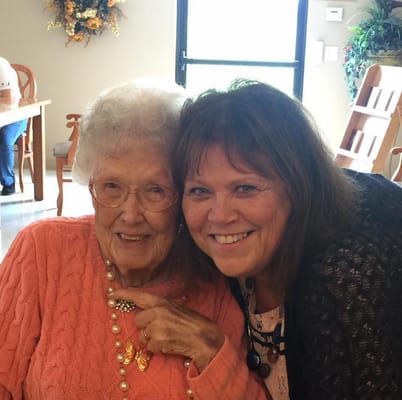 A smiling resident with staff member in a common area