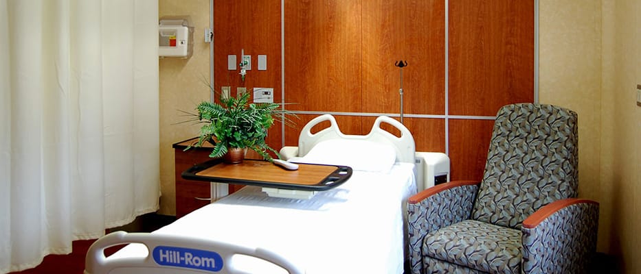Interior of a patient room with a bed and chair