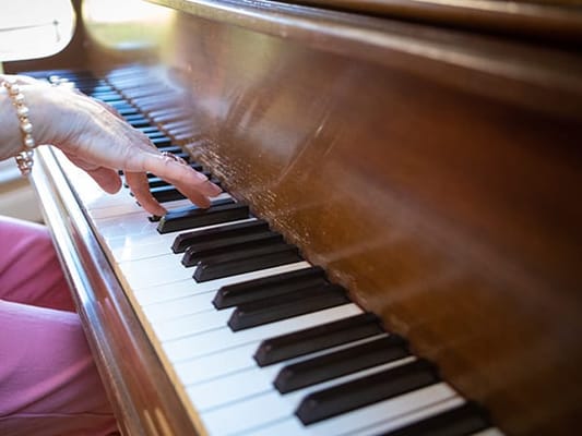 A resident playing the piano in a cozy interior setting