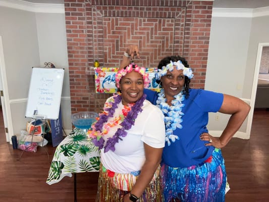 Two staff members celebrating with leis and smiles