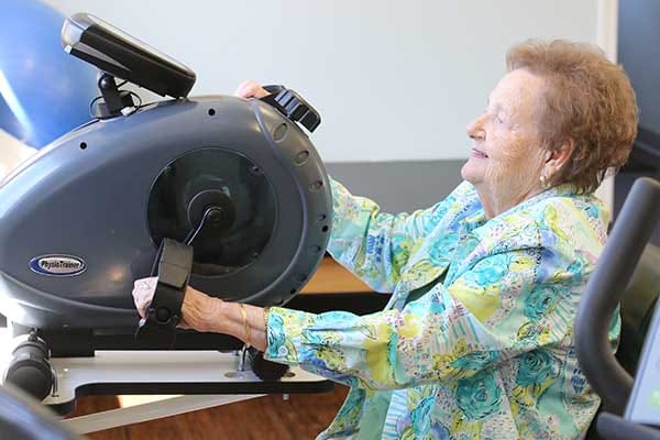 Senior woman exercising on a fitness machine in an activity room