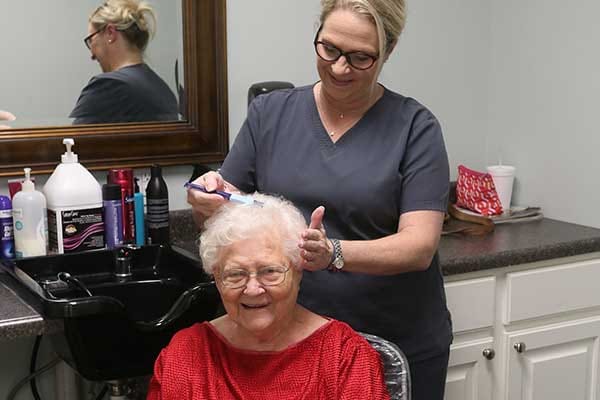 A stylist giving a haircut to a smiling resident