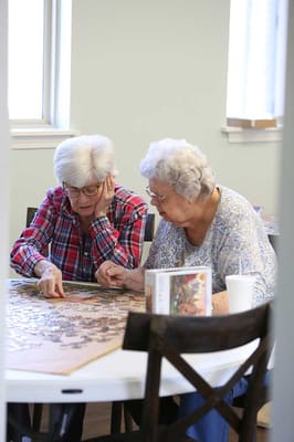 Two residents working on a puzzle at a table