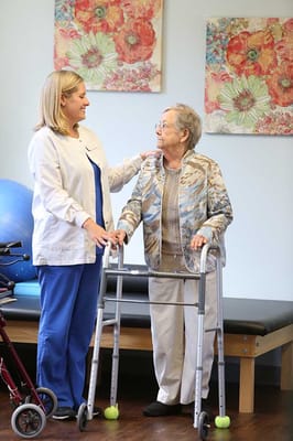 Staff assisting a resident with a walker in an activity room