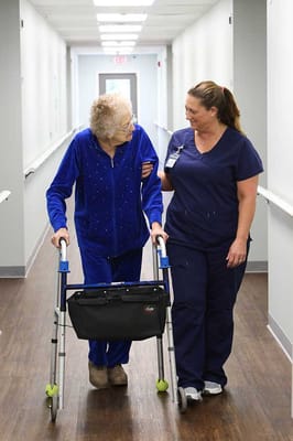 A caregiver assisting a resident in a hallway
