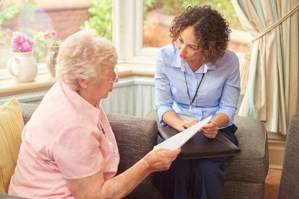 A caregiver meeting with a senior resident indoors.