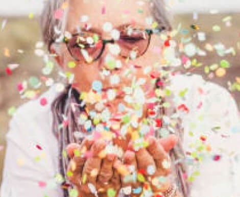 An elderly woman celebrating with colorful confetti