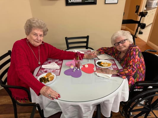 Two senior women enjoying a meal together at a table