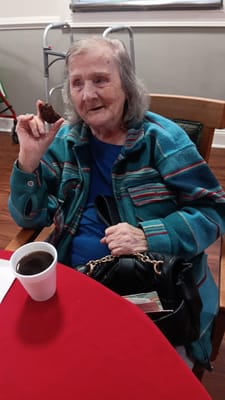 A resident enjoying a cookie and coffee in a common area