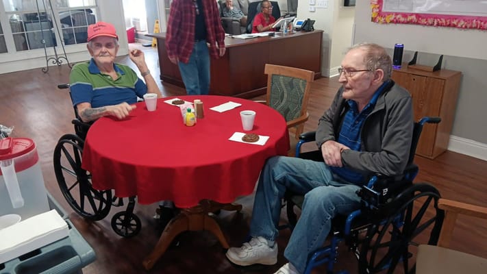 Two residents enjoying drinks and cookies at a table