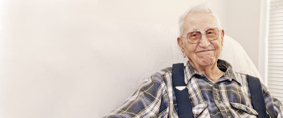 An older gentleman smiling in a cozy indoor setting