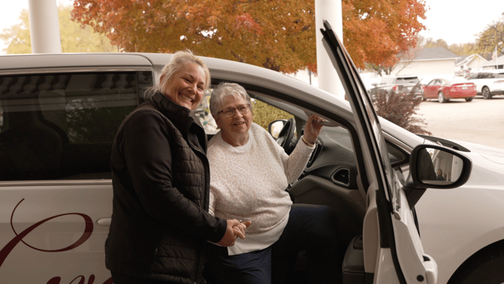 Two women smiling by a facility vehicle