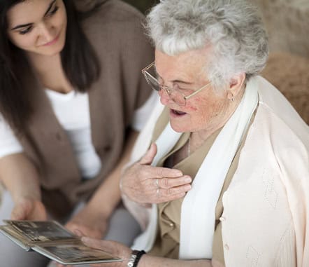 A caregiver and resident looking at a photo album together