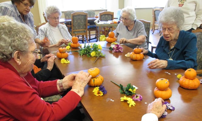 Residents participating in a craft activity with pumpkins