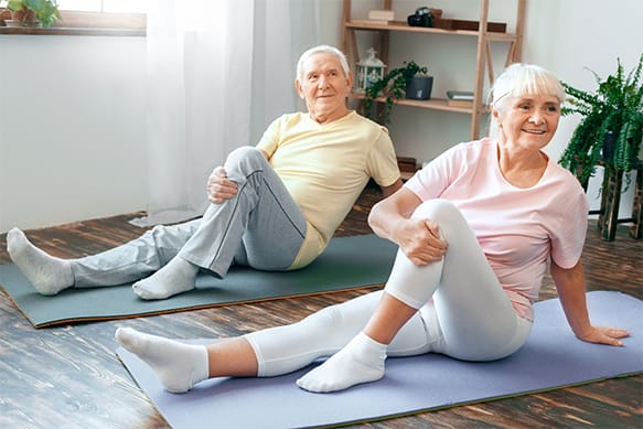 Two seniors participating in a stretching exercise indoors