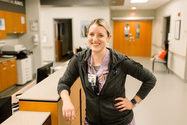 Staff member smiling at reception desk in a facility hallway