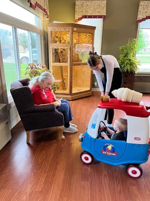 A resident enjoying time with staff and a child in the facility
