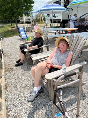 Two residents relaxing in outdoor seating with hats