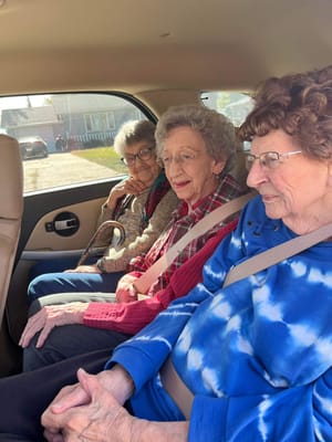 Three residents seated in the back of a vehicle.