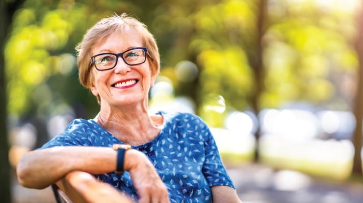 Smiling senior woman sitting outdoors in a park