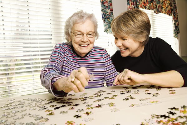 Senior resident and staff member enjoying a puzzle together