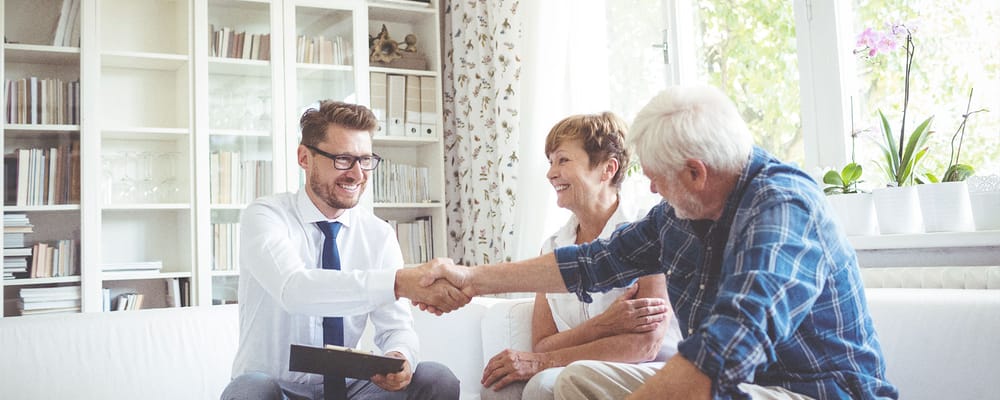Two residents shaking hands with a staff member in a bright room