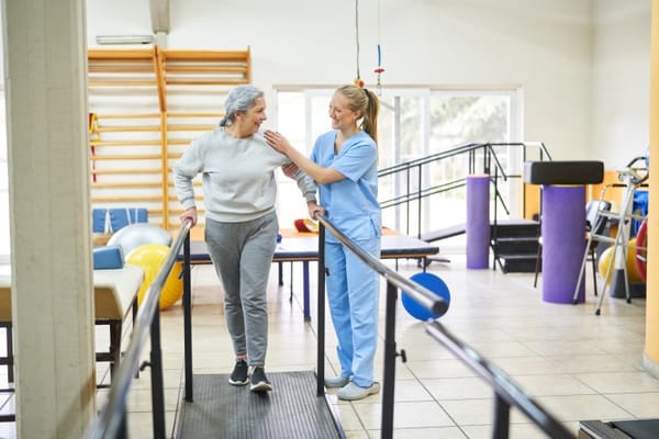 A resident and staff member in a physical therapy room