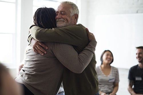 Residents embracing in a cheerful activity room