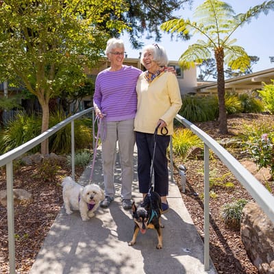 Two residents walking dogs along a garden pathway