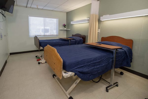 Shared resident room with adjustable beds and a bedside table