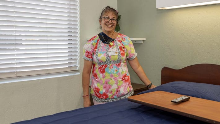 Staff member in a resident's room smiling