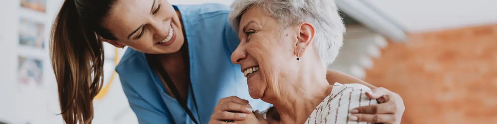 Caregiver assisting a smiling resident indoors