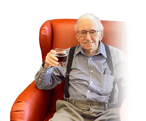 Smiling elderly man holding a drink in a comfortable chair