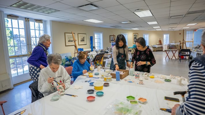 Residents participating in a pottery class in an activity room
