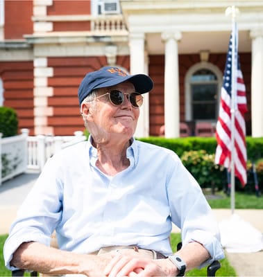 Senior resident enjoying the outdoors in front of the facility