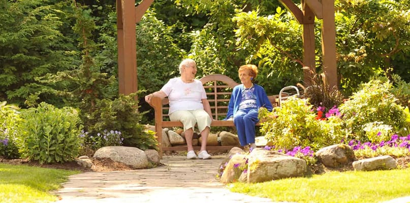 Two residents enjoying a garden bench in a well-maintained garden