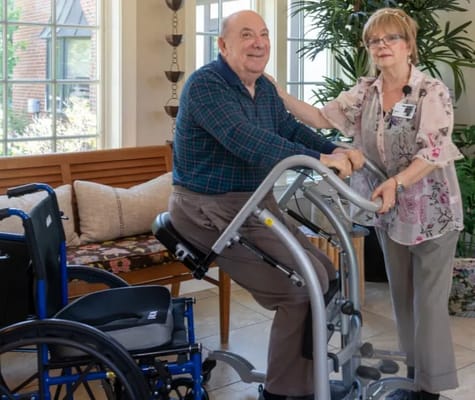 A resident with staff assistance in a bright common area