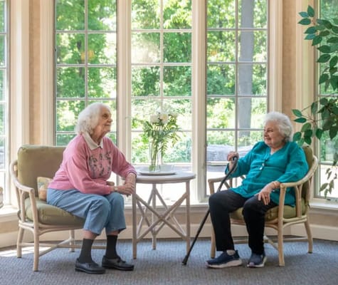 Two residents chatting in a sunlit common area